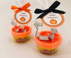 two plastic cups filled with halloween treats on top of a table