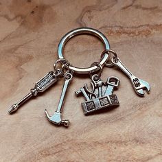 two keys are attached to each other on a wooden surface, one has a wrench and the other is a keychain