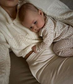 a woman holding a baby wrapped in a blanket while laying on top of a bed