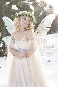 a woman dressed as a fairy standing in the snow with her hands on her hips