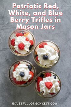 four desserts in small glass bowls with strawberries and blueberries on the top