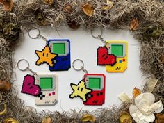 four pixel keychains with different designs on them in front of some dry grass