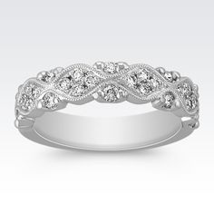 a white gold wedding band with diamonds on it's sides and an intricate design