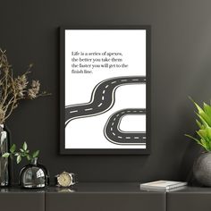 a black and white poster with a road going through it on the wall next to some plants