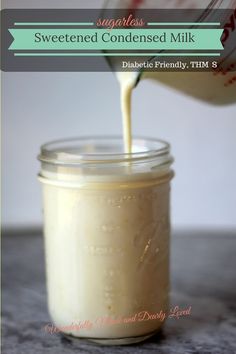 a glass jar filled with white liquid sitting on top of a counter next to a spoon