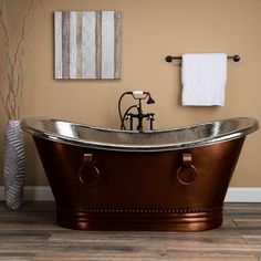 an old fashioned copper bathtub in a bathroom with wood flooring and beige walls