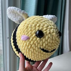 a hand holding up a small stuffed bee