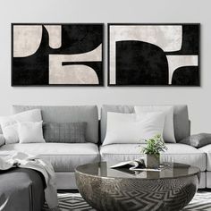 two black and white paintings hanging on the wall above a couch in a living room