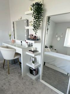 a bedroom with a bed, desk and mirror in it's corner next to a plant hanging on the wall