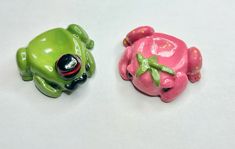 two toy frog figurines sitting next to each other