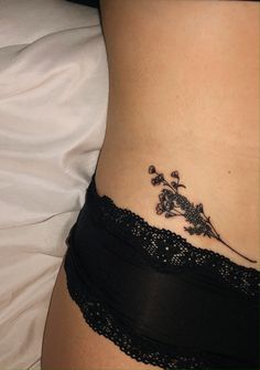 a small tattoo on the side of a woman's lower back stomach, with flowers growing out of it