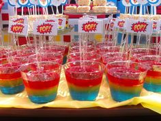 there are many glasses with different colored liquid in them on the table at this birthday party