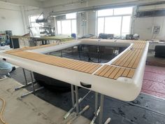 a boat being built in a factory with workers working on the wooden planks around it