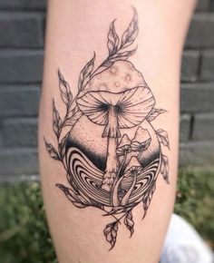 a black and white tattoo on the leg of a woman's thigh with an image of a mushroom