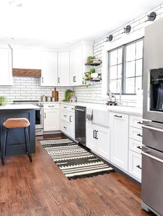 a kitchen with white cabinets and wood flooring, stainless steel appliances and an area rug