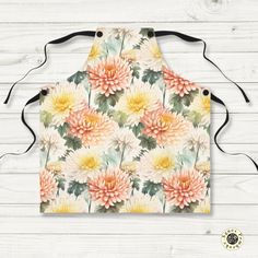 an apron with watercolor flowers on the front and back, hanging from a wooden wall