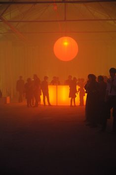 people are standing around in the fog at an art event with orange lights on them