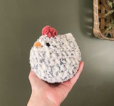 a hand holding a small crocheted chicken ornament