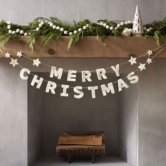 a merry christmas banner hanging over a fireplace