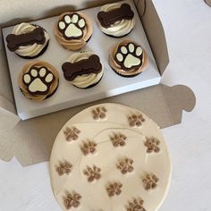 a box filled with cupcakes covered in frosting and dog paw prints on top