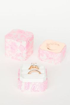 an engagement ring sits in a pink and white box next to it's matching wedding band