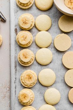 some cookies are sitting on a baking sheet with banana slices cut in half and another cookie is next to them