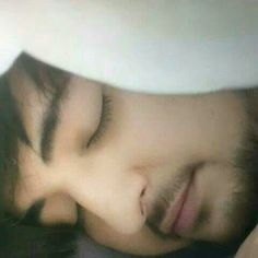 a close up of a person sleeping on a bed with his head resting on the pillow