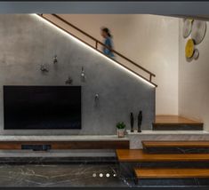 a woman is walking up the stairs in front of a television set on a wall