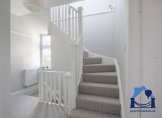 a white staircase with carpeted steps leading to the second floor and another door in the background