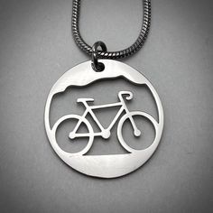 "Bicycle Circle Outline Pendant, large and petite Our bicycle pendant celebrates our love of adventure in the outdoors. Large Charm is 23mm or just shy of 1\", with 18\" Stainless snake snake chain with 2\" extender 18\"-20\". Petite Charm is 17.5 mm approximately 3/4 inch, with 18\" Stainless Link chain with 2\" extender 18\"-20\". Message us for other chain/cord options available including Black & Brown Leather or Cotton cord. Matching earrings available M O R E ∙ I N S P I R E D ∙ D E S I Coin Jewelry Diy, Bicycle Necklace, Surf Jewelry, Circle Outline, Coin Jewelry, Copper Pendants, Zipper Pulls, Diy Arts And Crafts, Cotton Cord