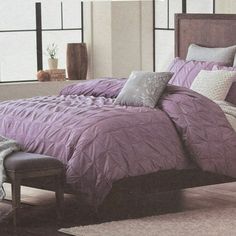 a large bed with purple comforter and pillows