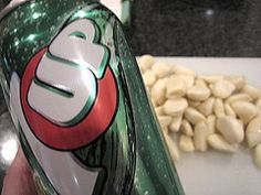 a hand holding a can of soda with peanuts in the background