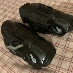 two black motorcycle boots sitting on top of a bed