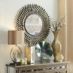 a table topped with vases and lamps next to a mirror on top of a wall