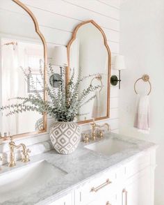 a bathroom with marble counter tops and two mirrors on the wall above it are gold faucets