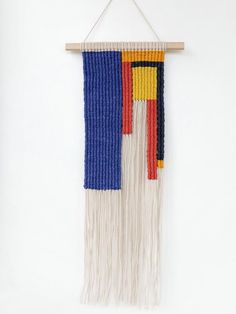 a wall hanging made out of yarn with fringes and beads on the bottom half