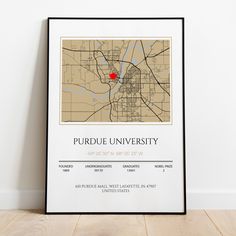 a framed map of the university of purdue with a red pin in it's center