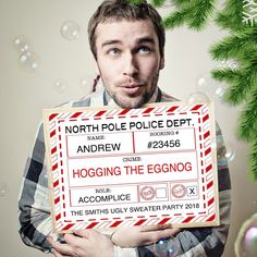 a man holding up a sign that says hogging the eggnog in front of a christmas tree