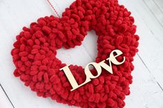 a heart shaped wreath with the word love hanging on it