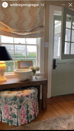 a room with a window, table and bench in it that has a lamp on top of it