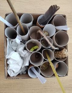 an open cardboard box filled with different types of paper cups and spoons on top of a wooden table