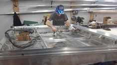 a man in a blue hat is working on a metal table with wires and other tools