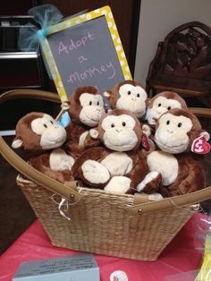 a basket filled with stuffed monkeys sitting on top of a table next to a sign