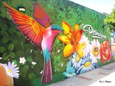 a colorful mural painted on the side of a building with flowers and birds in flight