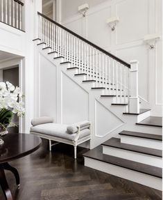 there is a white chair and some flowers on the table in front of the stairs