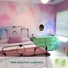 a bedroom with pink and green paint on the walls, dressers and bed in it