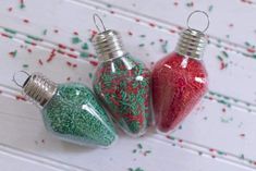 three christmas ornaments sitting on top of a white wooden table with sprinkles