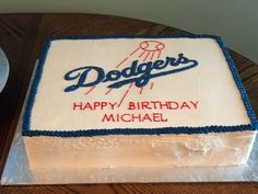 a dodgers birthday cake on a table next to a plate with a fork and knife