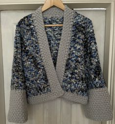 a gray and blue sweater hanging on a white door