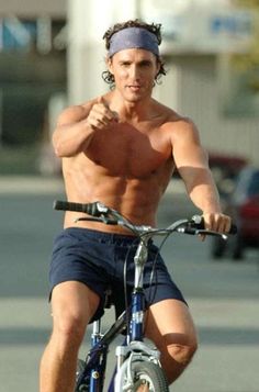 a shirtless man riding a bike with no shirt on and his arm in the air